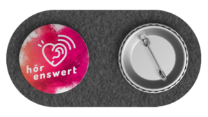 Links: Ansteckbutton mit Logo von HörEnswert, Rechts: Rückseite mit Anstecknadel