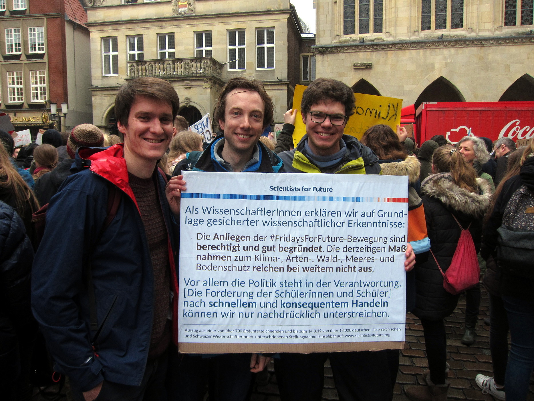 Drei demonstrierende Wissenschaftler auf der FridaysForFuture-Demo am 15.3.19 in Münster. Sie halten ein Banner in die Höhe mit folgendem Text: Als WissenschaftlerInnen erklären wir auf Grundlage gesicherter wissenschaftlicher Erkenntnisse: Die Anliegen der #FridaysForFuture-Bewegung sind berechtigt und gut begründet. Die derzeitigen Maßnahmen zum Klima-, Arten-, Wald-, Meeres- und Bodenschutz reichen bei Weitem nicht aus. Vor allem die Politik steht in der Verantwortung. Die Forderung der Schülerinnen und Schüler nach schnellem und konsequentem Handeln können wir nur nachdrücklich unterstützen.